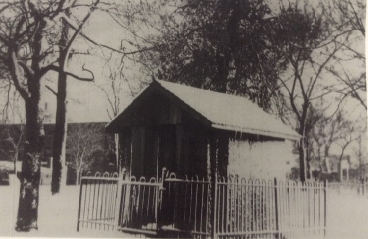Fort Conley, a small wooden building with a triangle roof and a short metal fence surrounding it.