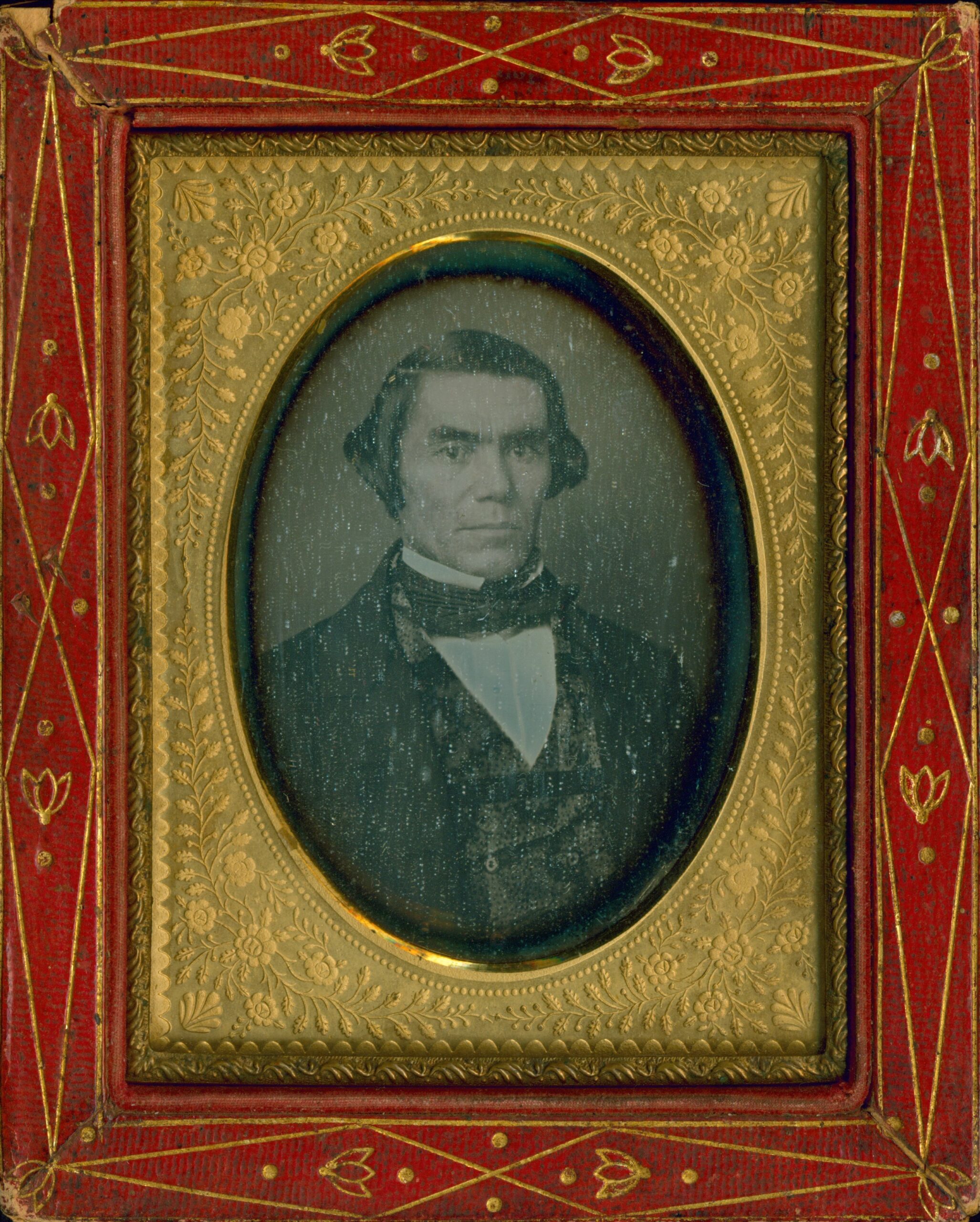 Portrait of Silas Armstrong. Placed in a red and gold frame, he wears a suit from the 1850s.