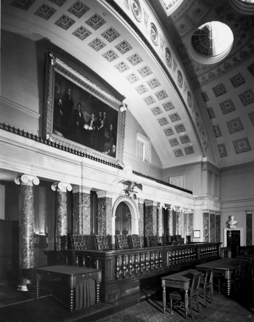 The old Supreme Court Chambers featuring an arched roof with a balcony and the bench with chairs for the Justices. No people are in the photo.