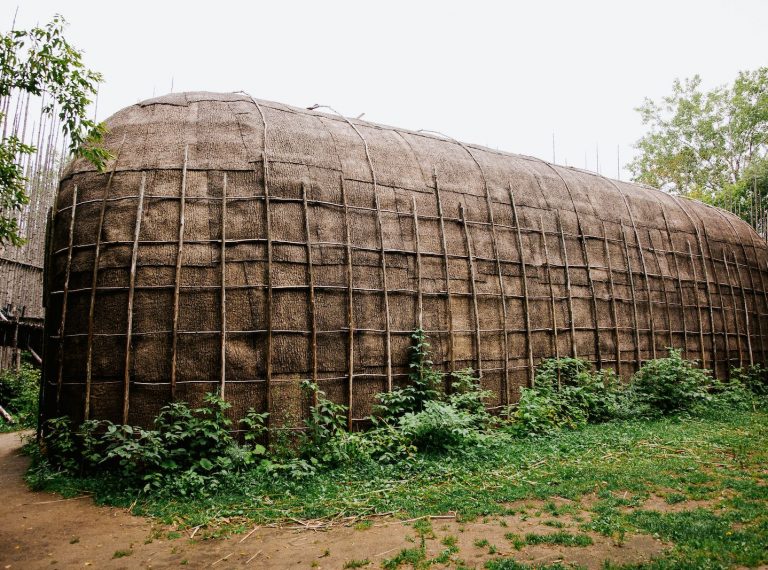 A traditional longhouse that the Wendat would have lived in in Canada. It is a long wooden structure made of bark and wood with a rounded roof.